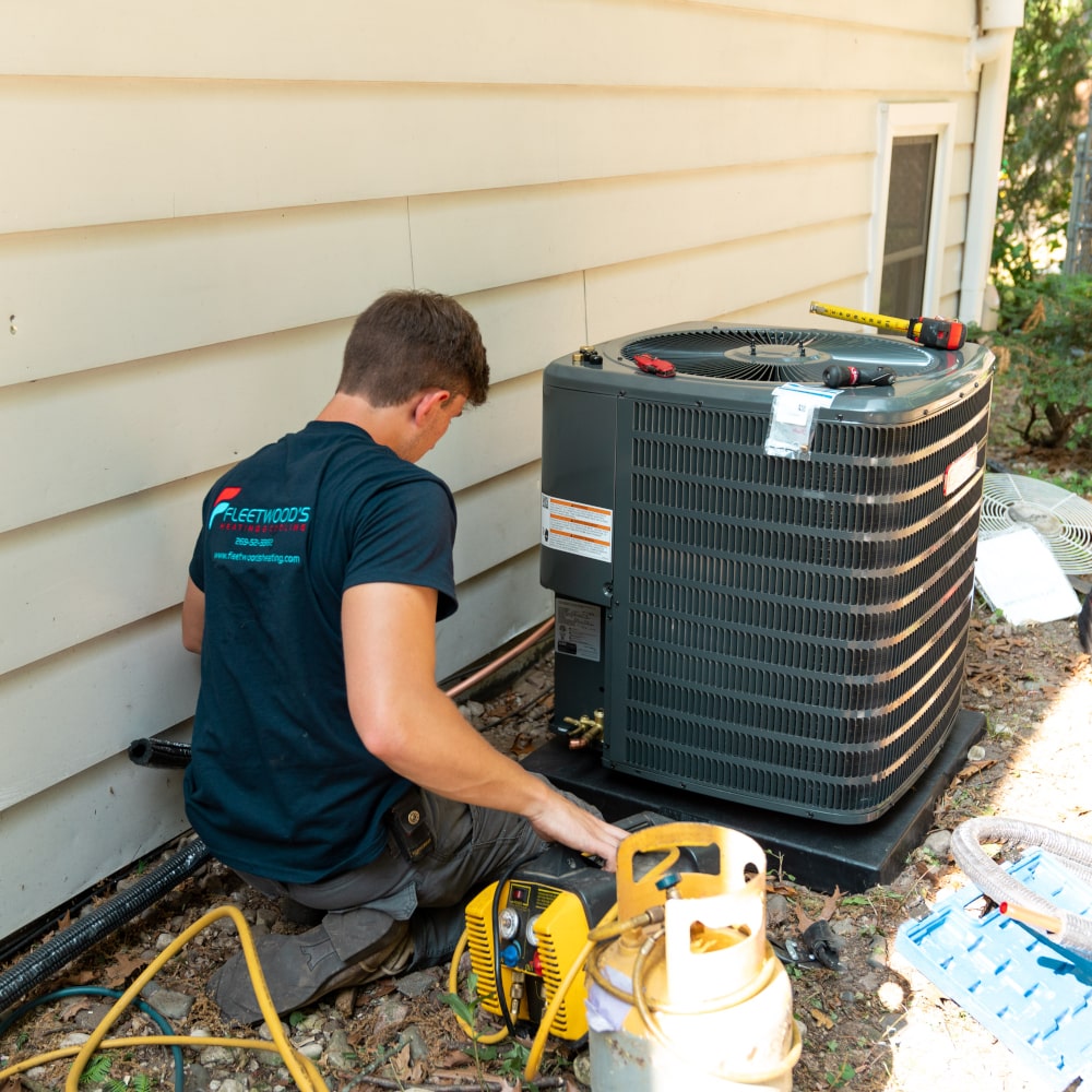 A man in a branded shirt fixing an air conditioner in a professional photo.