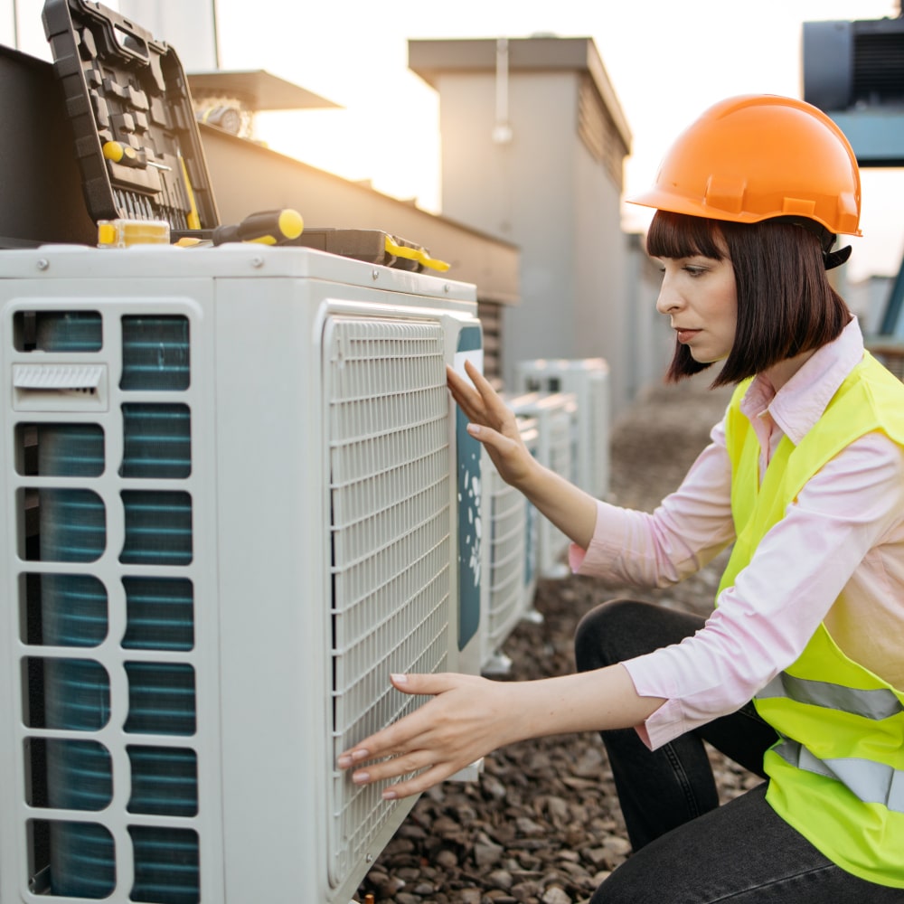 A stock image of a woman fixing an air conditioner.