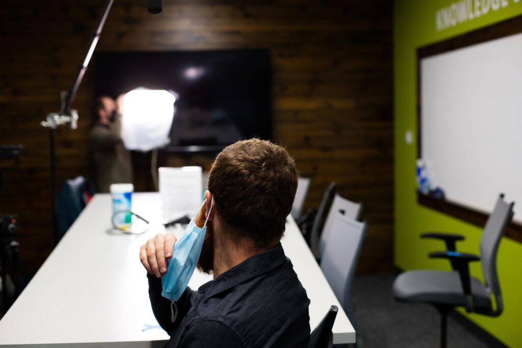 A man removing a mask in a conference room.